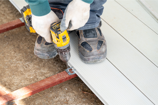 Man assembling composite deck using cordless screwdriver